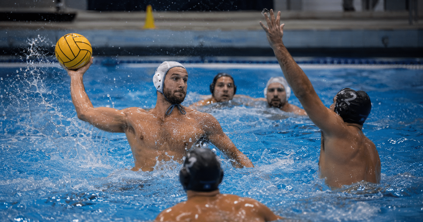 Jugadores adultos de waterpolo en plena acción de juego con pelota