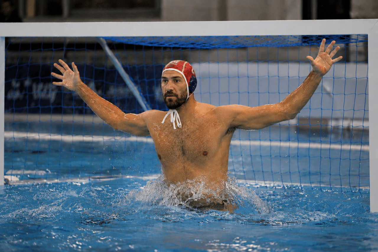 Portero adulto de waterpolo en posición vertical frente a la portería